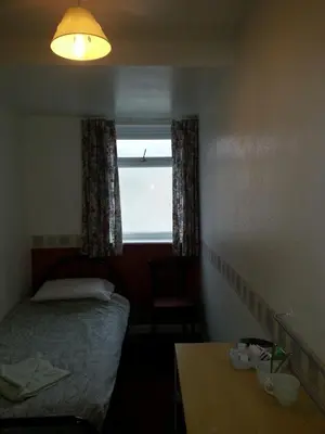 a small bedroom with a bed and a window at Jesmond International Hotel in Blackpool