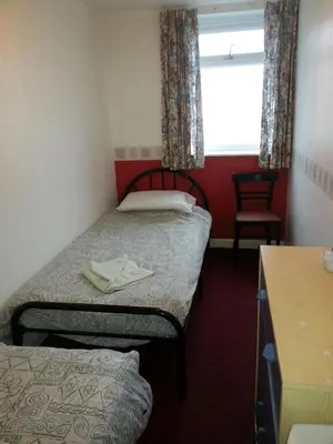 a small room with two beds and a window at Jesmond International Hotel in Blackpool