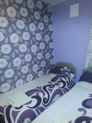 a bedroom with two beds and a floral wallpaper at Jesmond International Hotel in Blackpool