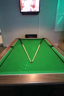 a green pool table with a tv in a room at Jesmond International Hotel in Blackpool