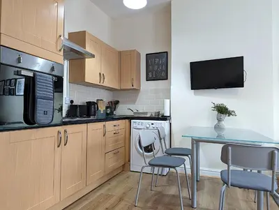 a kitchen with a table and two chairs and a microwave at Lovely Studio in Anfield Near Centre Free Parking in Liverpool