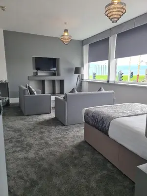 a bedroom with a bed and two couches and a tv at Royal Seabank Hotel in Blackpool