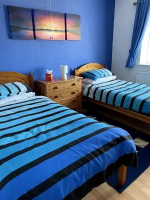 two beds in a bedroom with blue walls at Quiet secluded two bedroom bungalow with parking in Cleveleys