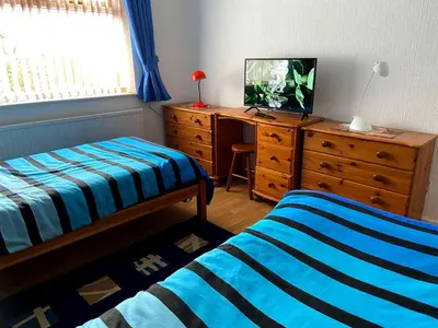 a bedroom with two beds and a dresser with a tv at Quiet secluded two bedroom bungalow with parking in Cleveleys