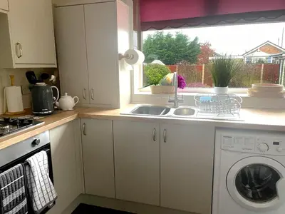 a kitchen with a sink and a washing machine at Quiet secluded two bedroom bungalow with parking in Cleveleys