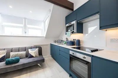 a kitchen with blue cabinets and a couch at Morecambe Bay Free Parking By Beach Front Sea View in Morecambe