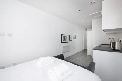 a white kitchen with a table with towels on it at GuestReady - Monochromatic Retreat in Liverpool