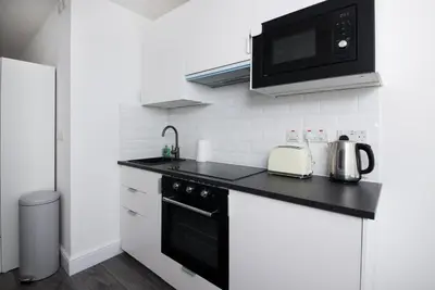 a kitchen with a black counter top and a microwave at GuestReady - Monochromatic Retreat in Liverpool