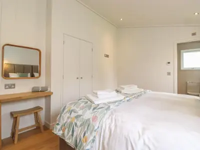 a white bedroom with a bed and a mirror at The Beeches in Ulverston