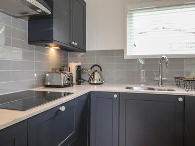 a kitchen with black cabinets and a sink at Blackthorn Copse in Ulverston