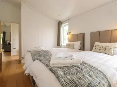 a white bedroom with two beds with towels on them at The Brambles in Ulverston