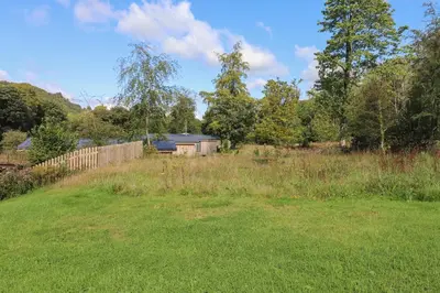 a field of grass with a fence and trees at The Brambles in Ulverston