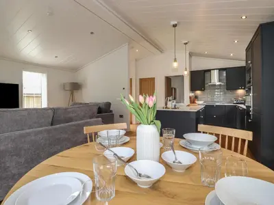 a dining room table with white plates and flowers on it at Millstream Ridge in Ulverston