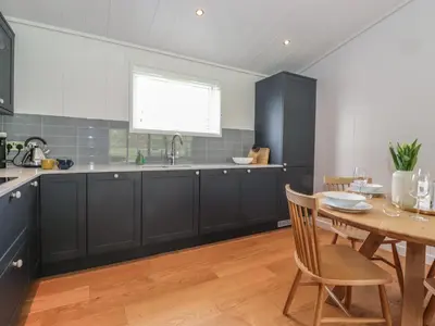 a kitchen with black cabinets and a wooden table at Corning Mill View in Ulverston