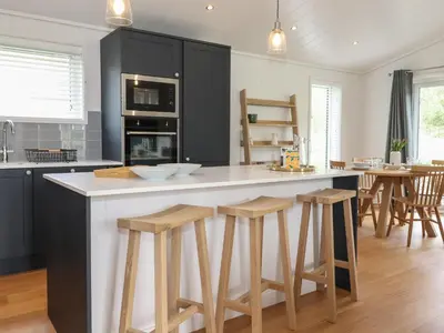 a kitchen with black cabinets and a counter with stools at Ash Thwaite in Ulverston