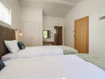 a bedroom with two beds and a door at Hawthorn Croft in Ulverston