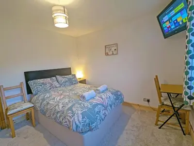 a bedroom with a bed and a tv and a chair at Double Room l Large TV l Great Transport Links in Bolton