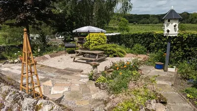 a garden with a bench and an umbrella at The Dairy at Brackenthwaite Farm in Carnforth