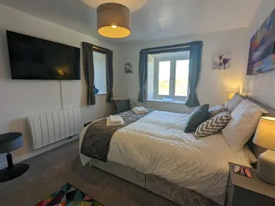 a bedroom with a large bed and a window at Corner Cottage at Brackenthwaite Farm in Carnforth