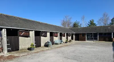 a barn with a table and chairs in front of it at Corner Cottage at Brackenthwaite Farm in Carnforth