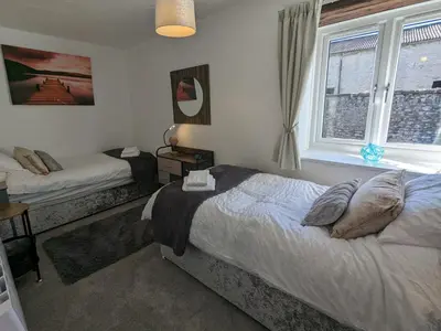 a bedroom with two beds and a window at The Coach House at Brackenthwaite Farm in Carnforth