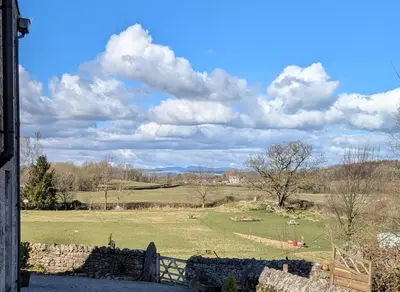 a field with a fence and animals in a field at The Coach House at Brackenthwaite Farm in Carnforth