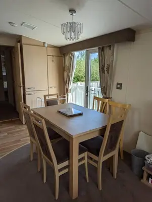 a dining room table with chairs and a laptop on it at 6 berth holiday home on Ocean Edge near Morecambe in Heysham
