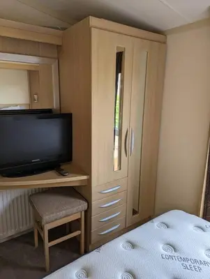 a bedroom with a bed and a tv and a cabinet at 6 berth holiday home on Ocean Edge near Morecambe in Heysham