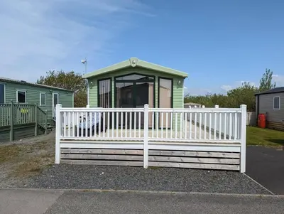 a white fence in front of a small house at 6 berth holiday home on Ocean Edge near Morecambe in Heysham