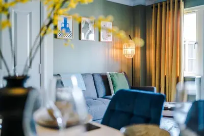 a living room with a blue couch and a table at Newly Refurbished 3 Double Bedroom Knowsley Liverpool Townhouse in Knowsley