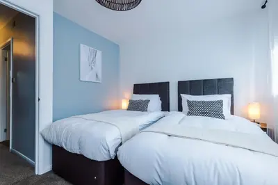 a bedroom with two beds and a blue wall at Newly Refurbished 3 Double Bedroom Knowsley Liverpool Townhouse in Knowsley