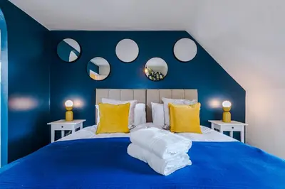 a blue bedroom with a large bed with yellow pillows at Newly Refurbished 3 Double Bedroom Knowsley Liverpool Townhouse in Knowsley