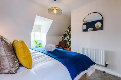 a bedroom with a blue and white bed with a mirror at Newly Refurbished 3 Double Bedroom Knowsley Liverpool Townhouse in Knowsley