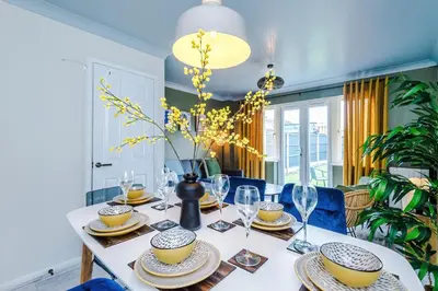 a dining room table with plates and wine glasses at Newly Refurbished 3 Double Bedroom Knowsley Liverpool Townhouse in Knowsley