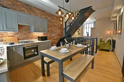 a kitchen and dining room with a table and a staircase at Quirky cottage set in Clitheroe in Clitheroe