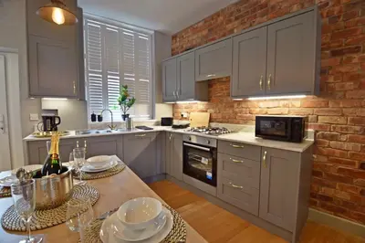 a kitchen with white cabinets and a brick wall at Quirky cottage set in Clitheroe in Clitheroe