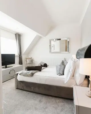 a white bedroom with a bed and a television at Birkby Lodge Escape in Lytham St Annes