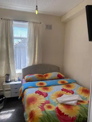 a bedroom with a bed with a colorful comforter and a window at Crosby Hotel in Blackpool