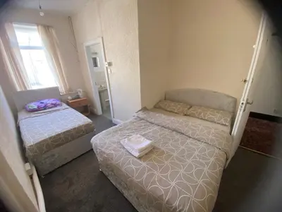 a small bedroom with two beds and a window at Crosby Hotel in Blackpool