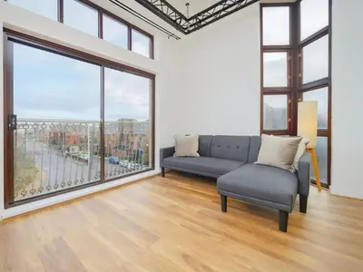 a living room with a couch and a large window at Baltic Dockside Apartment, Free Parking in Liverpool