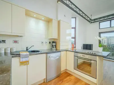 a kitchen with white cabinets and a sink and a dishwasher at Baltic Dockside Apartment, Free Parking in Liverpool