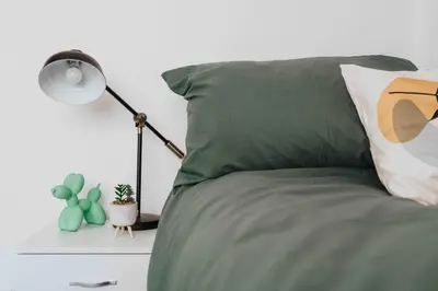a bed with a green pillow and a lamp at 10Min Walk to Stadium SofaBed WM & Dishwasher in Liverpool