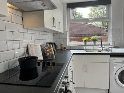 a kitchen with a sink and a stove top oven at Modernised central Wigan townhouse sleeps up to 6 in Wigan