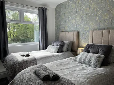 a bedroom with two beds and a window at Modernised central Wigan townhouse sleeps up to 6 in Wigan