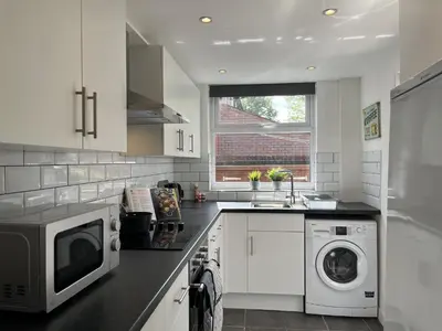 a kitchen with a microwave and a washer and dryer at Modernised central Wigan townhouse sleeps up to 6 in Wigan