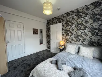 a bedroom with a bed with a floral wallpaper at Modernised central Wigan townhouse sleeps up to 6 in Wigan
