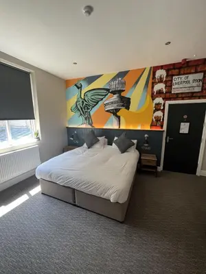 a bedroom with a bed with a painting on the wall at Fenwick Sunrise Hotel in Liverpool