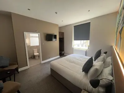 a bedroom with a large bed and a television at Fenwick Sunrise Hotel in Liverpool