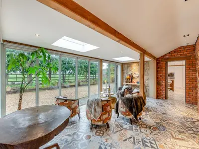 a living room with a table and chairs and windows at The Stables in Longridge