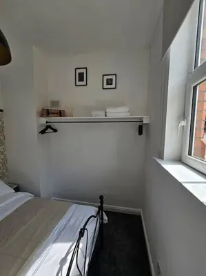 a white bedroom with a bed and a window at Shakespeare's Snug in Prescot